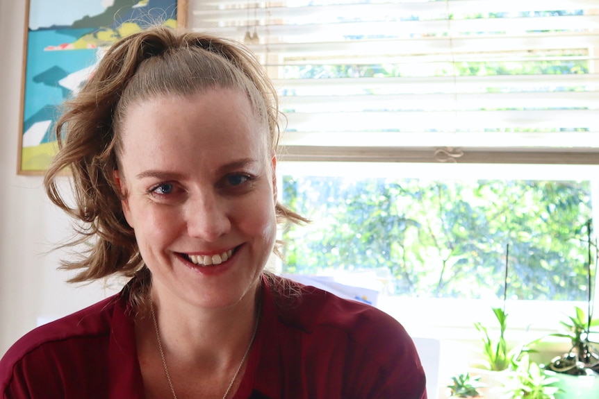 Stephanie smiles at the camera inside wearing a red shirt.