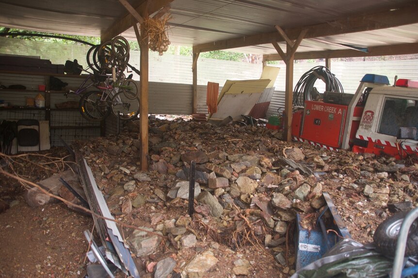 Rubble piled waist-deep under a shed roof, covering half a fire truck.