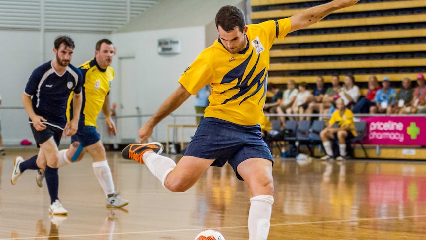 A man swings his leg in preparation of kicking a soccer ball