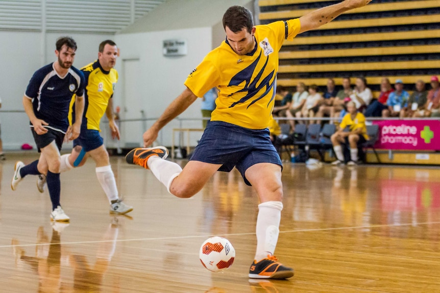 A man swings his leg in preparation of kicking a soccer ball