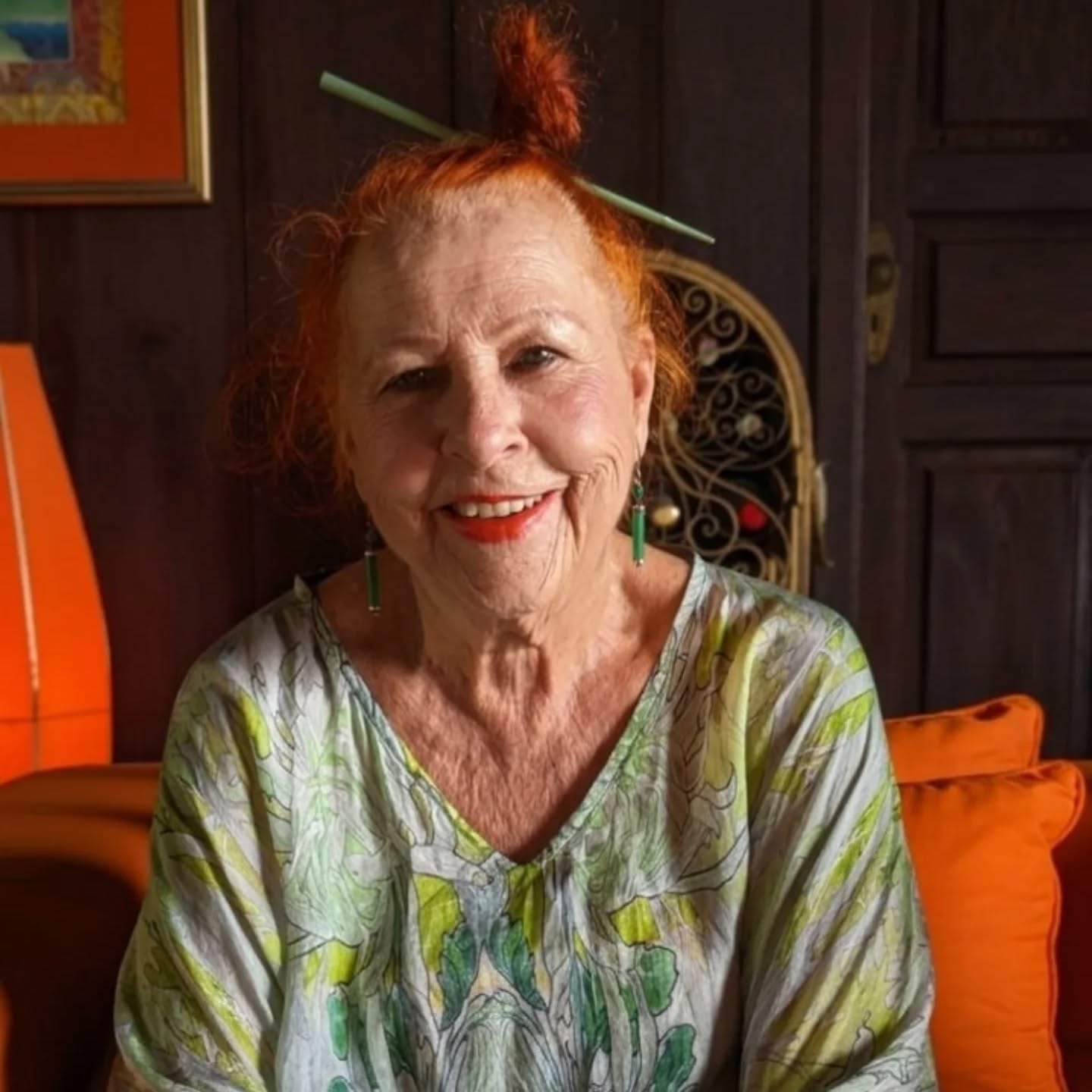 A middle-aged woman with red hair smiles while posing for a portrait.
