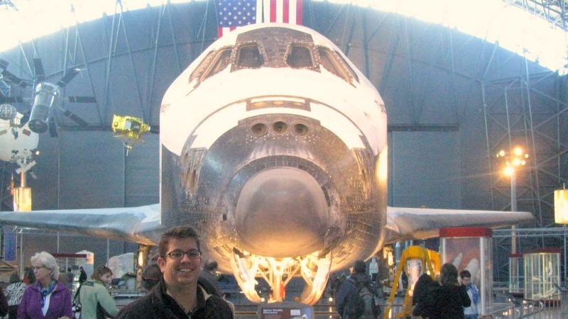 Man in crowd, in front of space shuttle museum exhibit