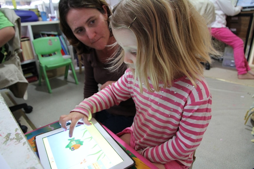 A mother helping her daughter doing school work on a tablet