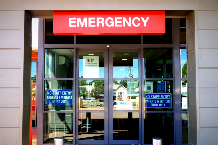 A sign that says "Emergency" above a set of doors at a hospital.