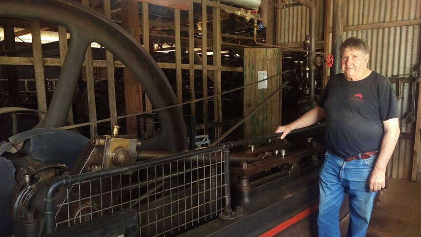 The president of the Blackall Woolscour committee Bob 'Willow' Wilson standing next to the 112 year old steam engine.