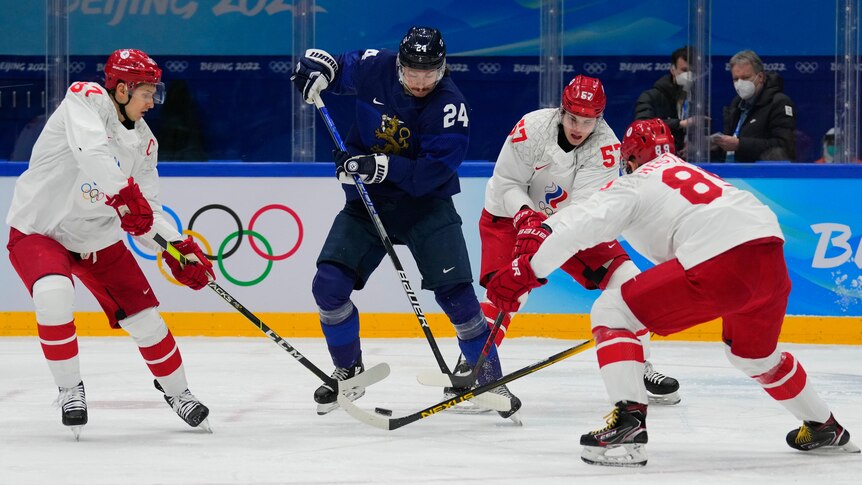 Finland tries to control the puck surrounded by Russian Olympic Committee at the 2022 Winter Olympics. 