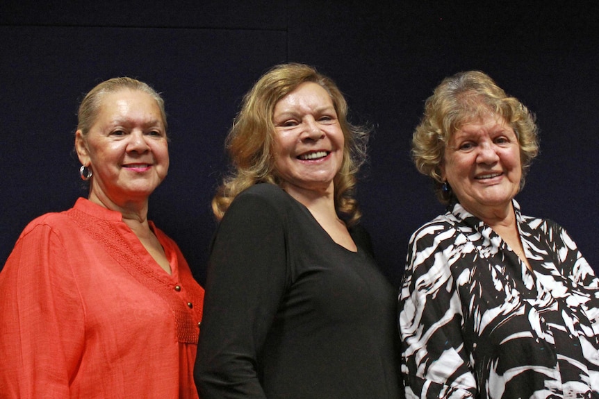 The three members of the Sapphires singing group. They are smiling and the background behind them is black.