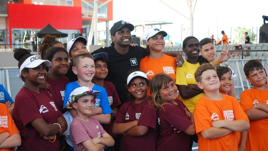 Baker Boy smiles at the camera with a group of children