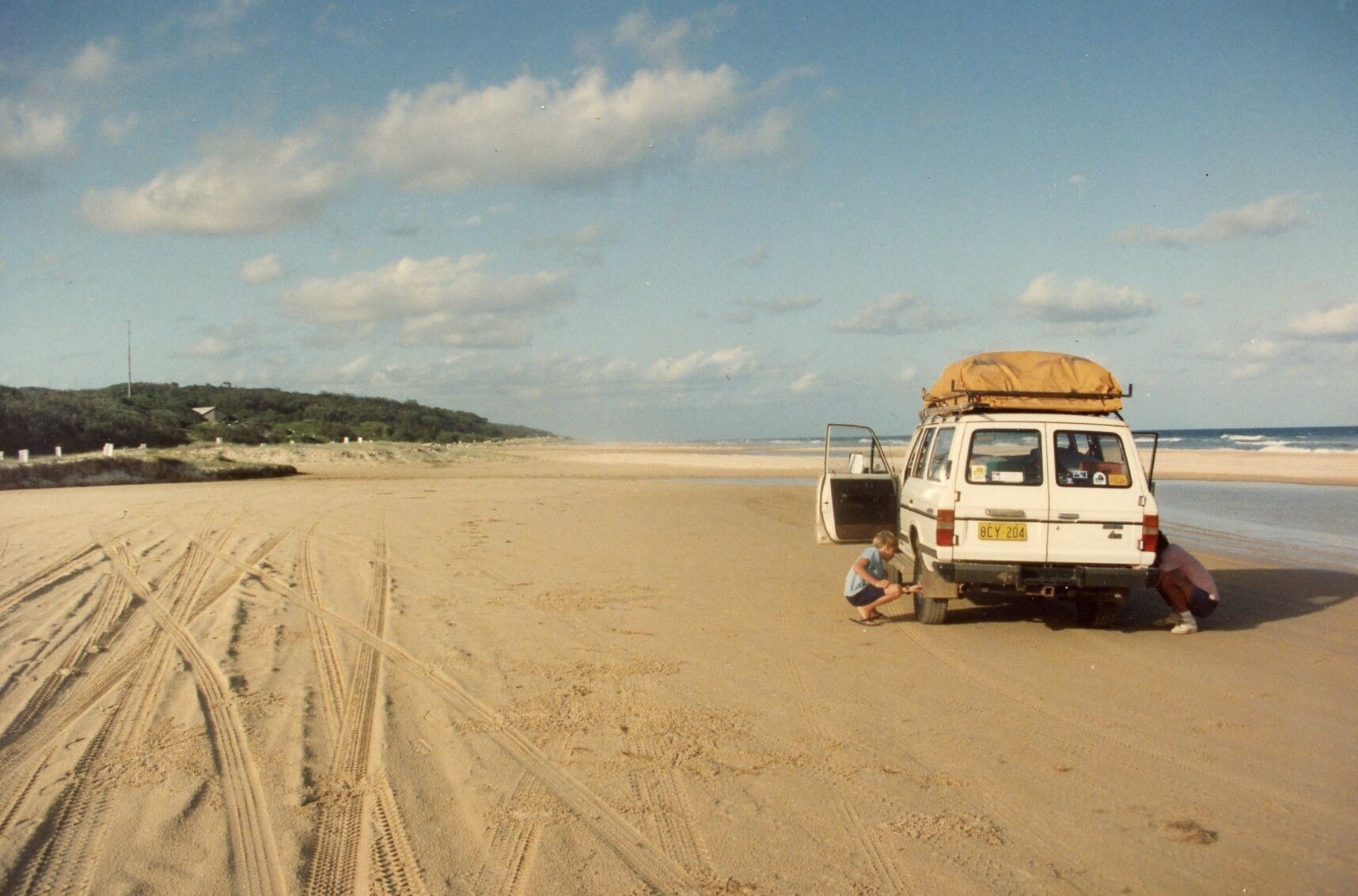 Una mujer y un hombre empacando una caravana mientras están en la playa