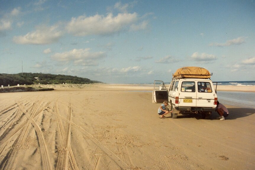 A woman and man packing a caravan while on a beach