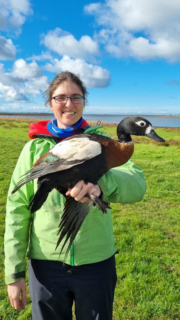 Michelle Wille stands near a lake holding a duck