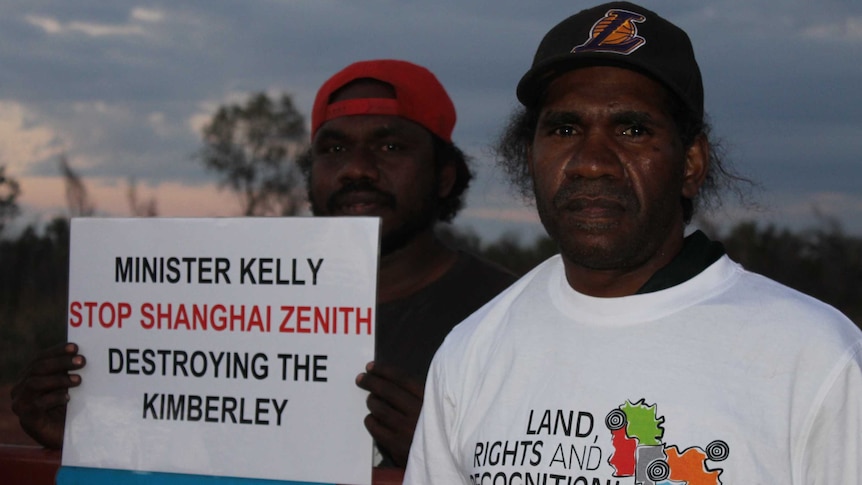Two aboriginal men holding up a protest sign