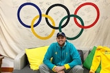 David McKeon sits underneath a large Olympic flag with signatures on it.