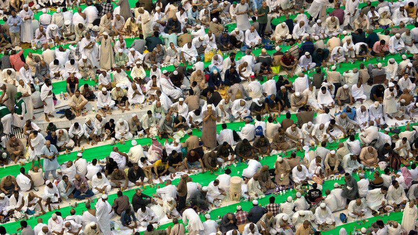 Rows of Muslim worshippers at the Grand Mosque in Mecca seated before food and drink they will consume after sunset.