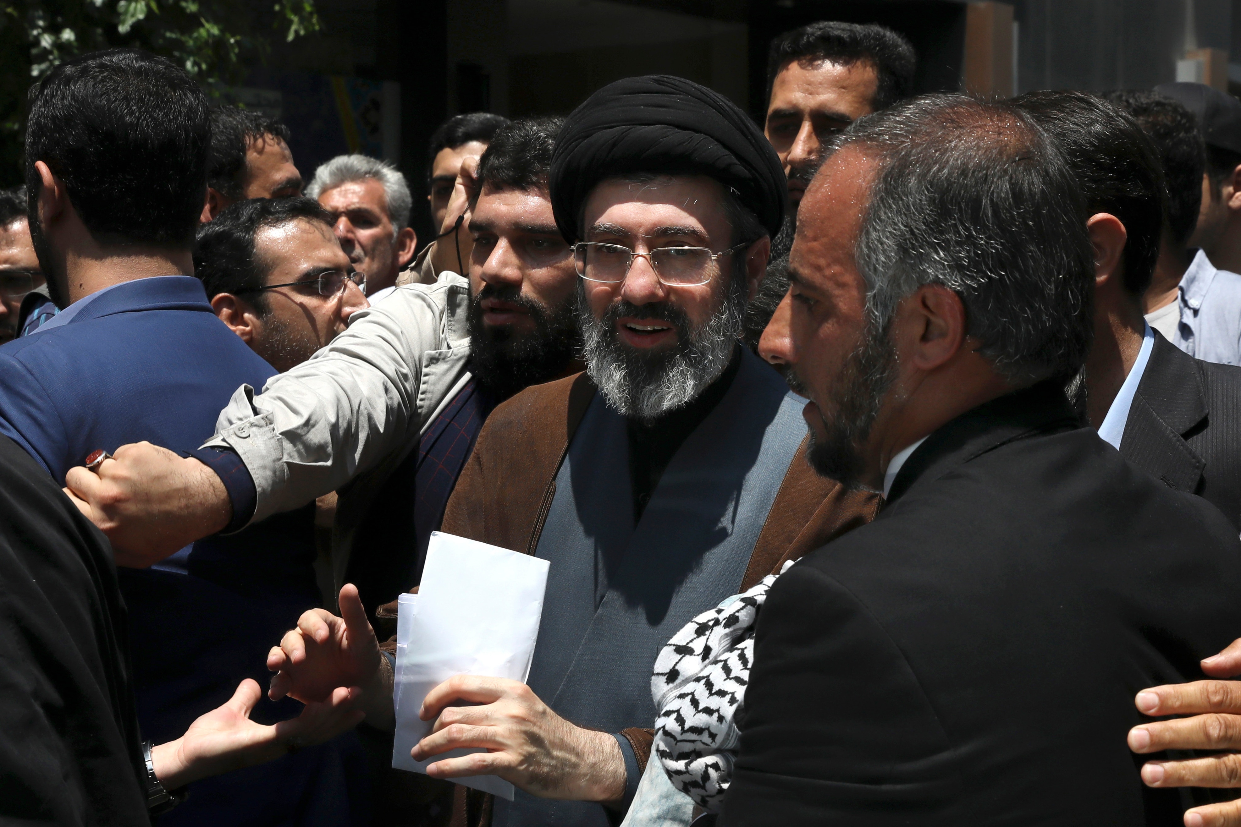 Mojtaba Khamenei, wearing a black turban, standing in a crowd. 