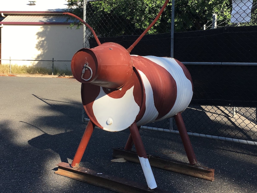 Metal sculpture made from barrels in the shape of a cow painted brown and white