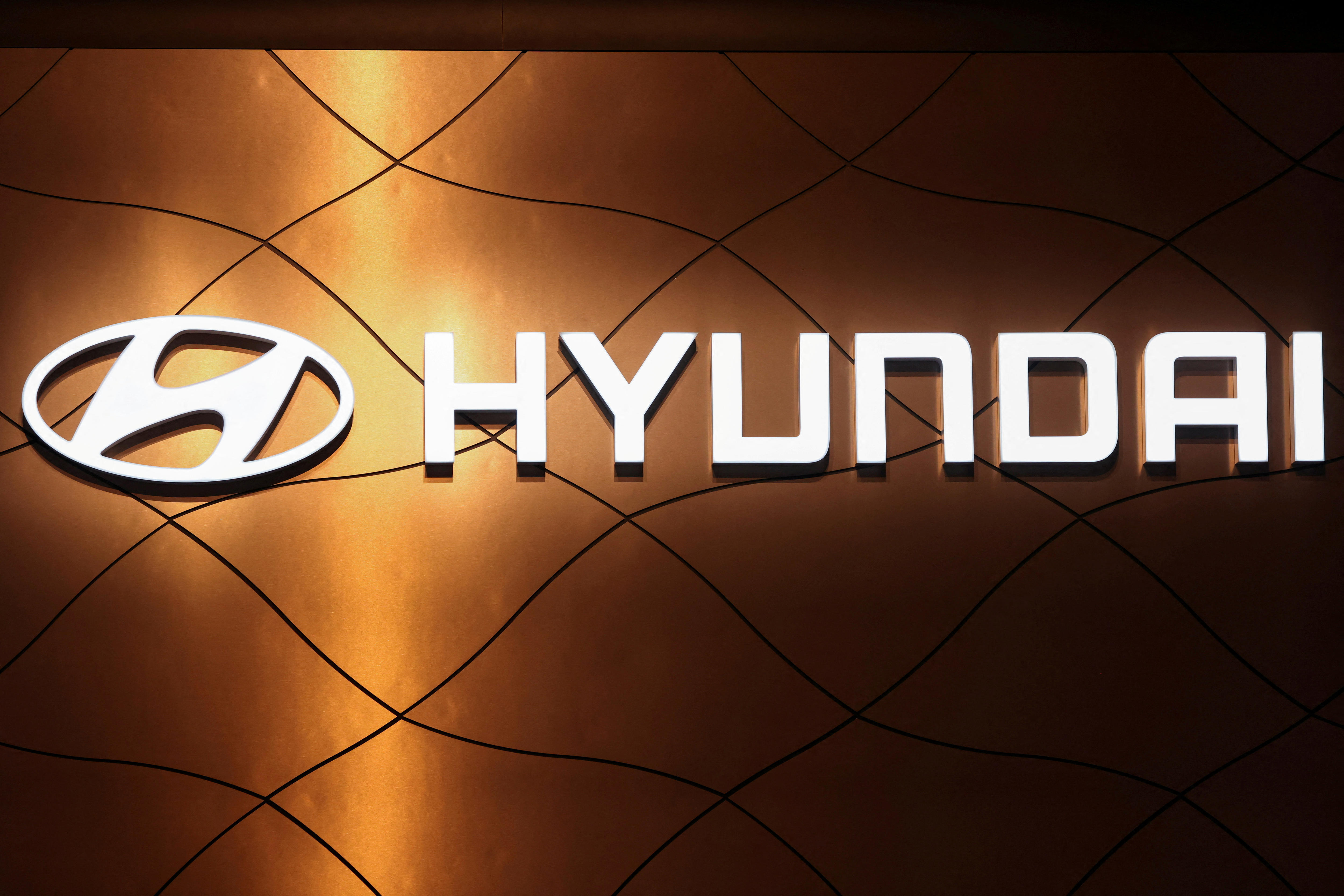 The word Hyundai is illuminated with the logo beside it in front of a brass coloured background