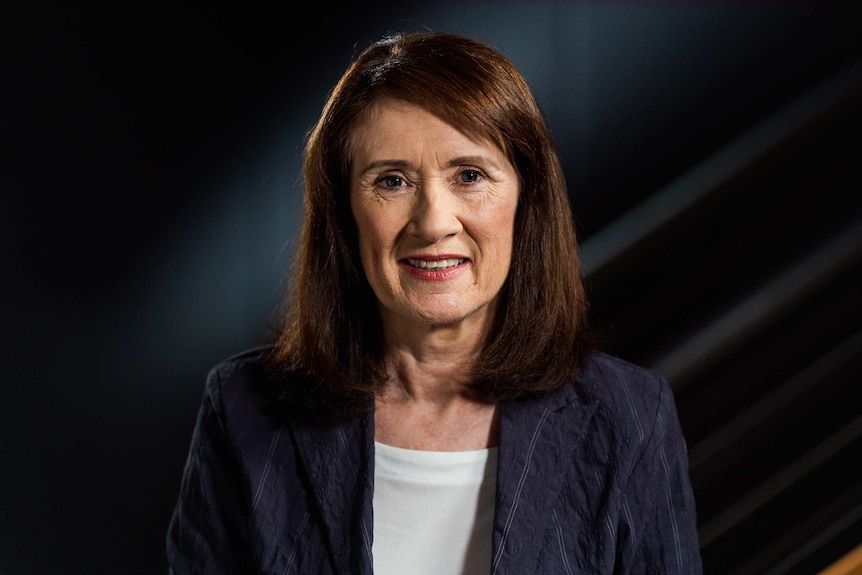 A woman in a studio smiles for a photo