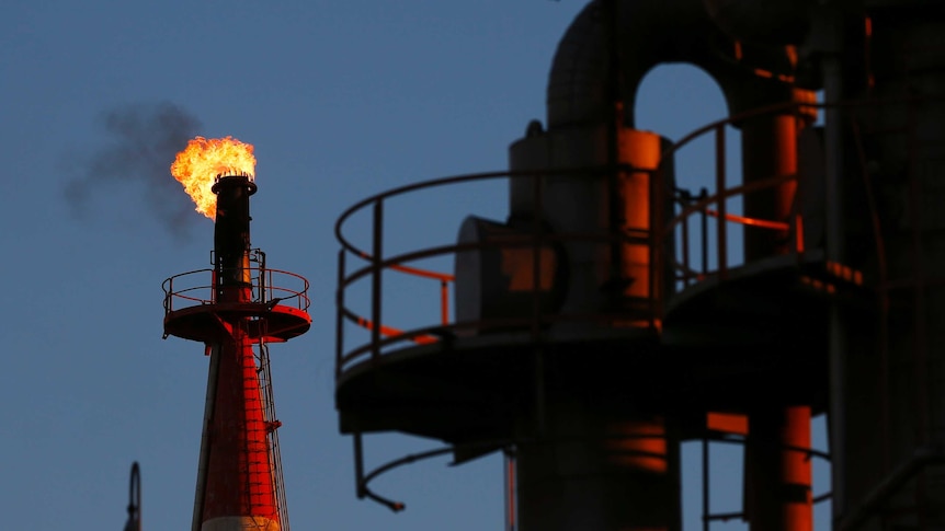 A flame shoots out of a chimney at a petro-industrial factory
