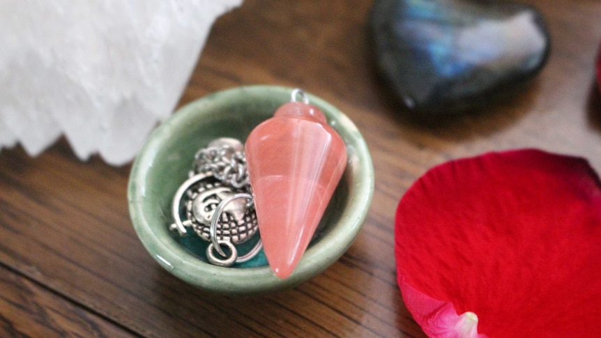 A small pot with a pink crystal and silver jewellery in it