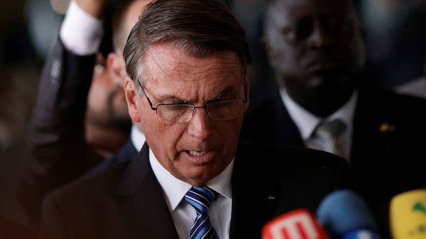 Jair Bolsonaro is pictured during a press statement, he talks while looking down