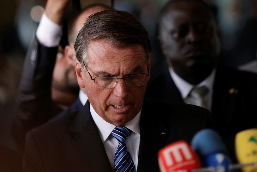 Jair Bolsonaro is pictured during a press statement, he talks while looking down