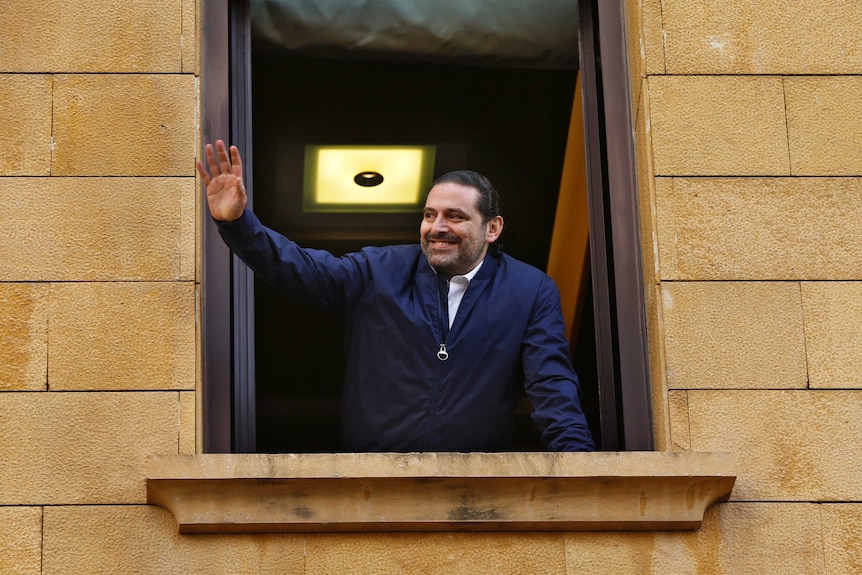 Saad Hariri waves to his supporters from a window of his residence.