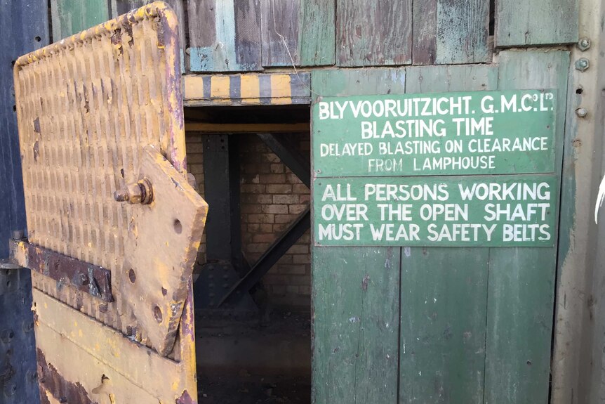 A faded safety notice can be seen near the entrance to a mine shaft.