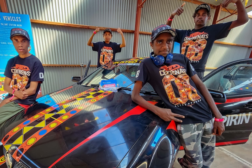 Young aboriginal men stand around a restored vehicle