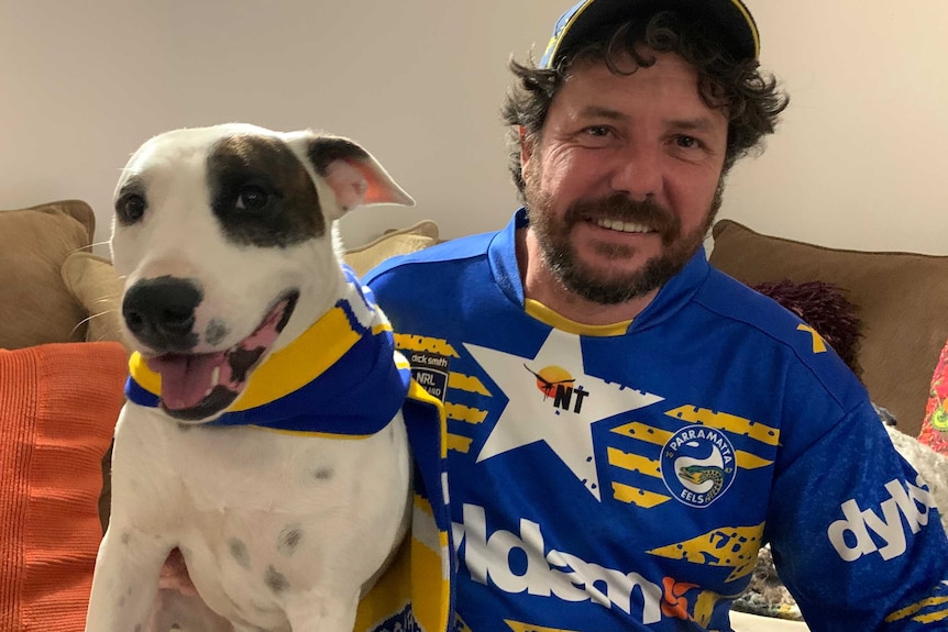 Man with his dog both wearing Paramatta sports gear