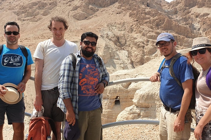 Five adults standing in front of a cave