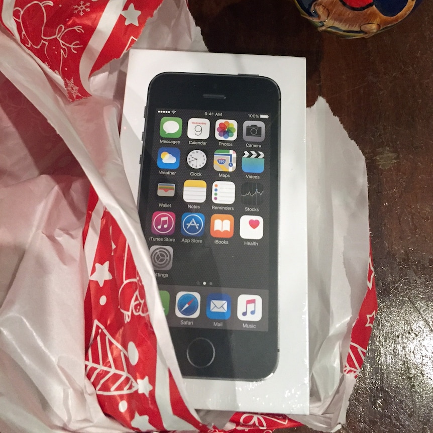 An unwrapped mobile phone under a Christmas tree.