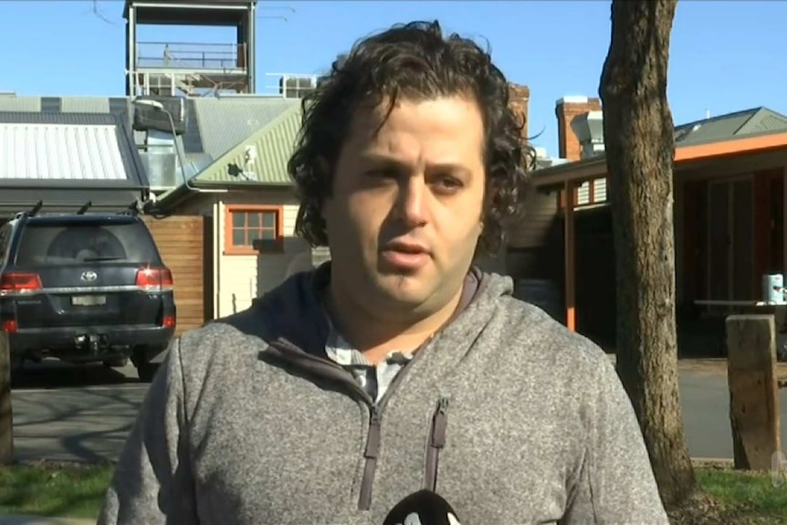 man stands outside his restaurant