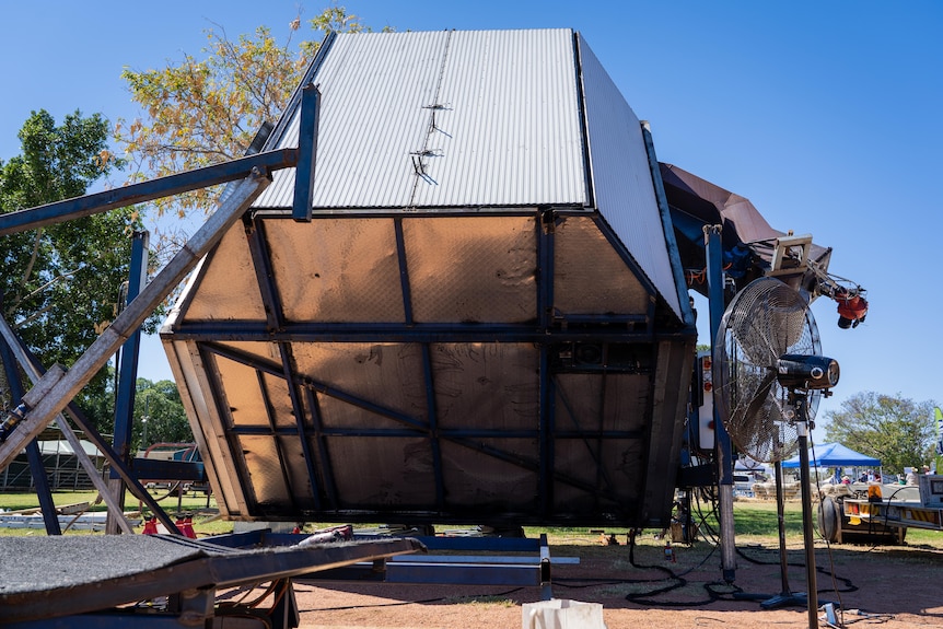 A huge hexagonal shed-like object rotates on an axis.