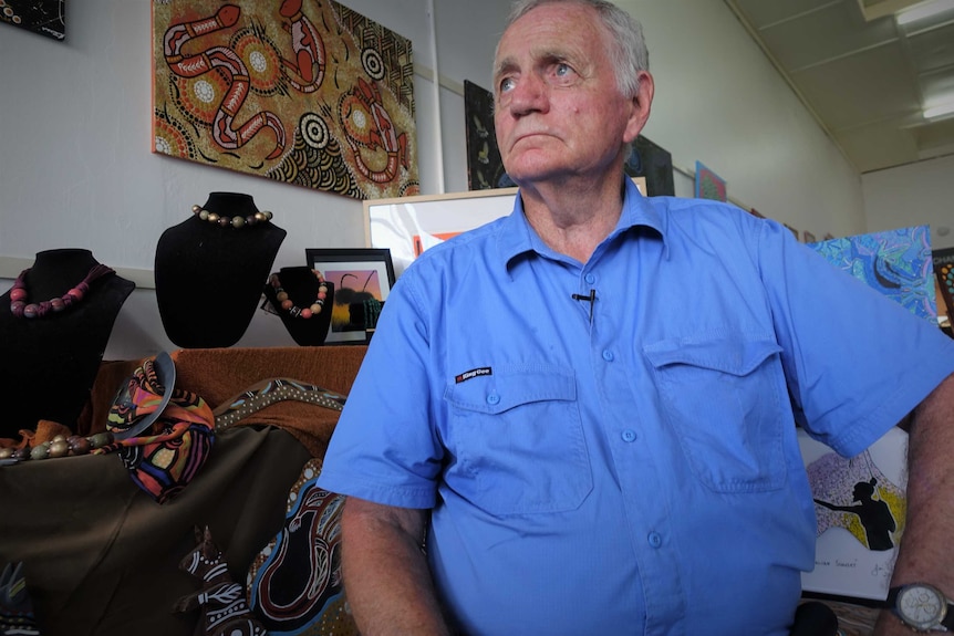 Pete sits in the workshop in front of traditional Aboriginal artwork.