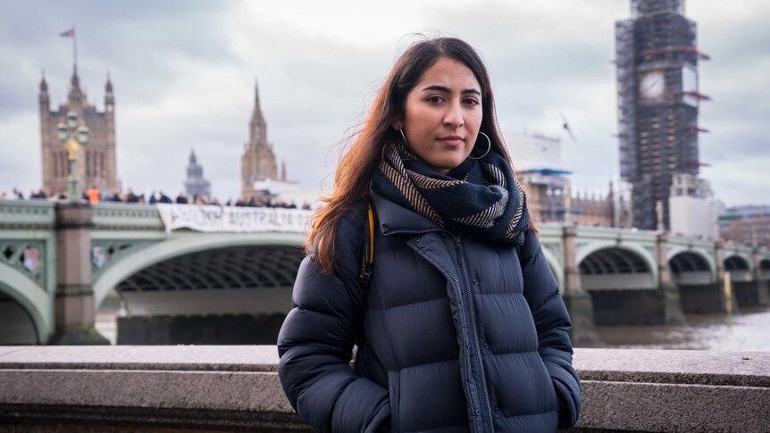 A woman dressed in a warm coat stands in front of the Westminster Bridge protest.