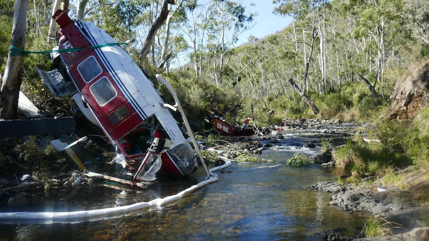 A damaged helicopter in a river bed in a national park.