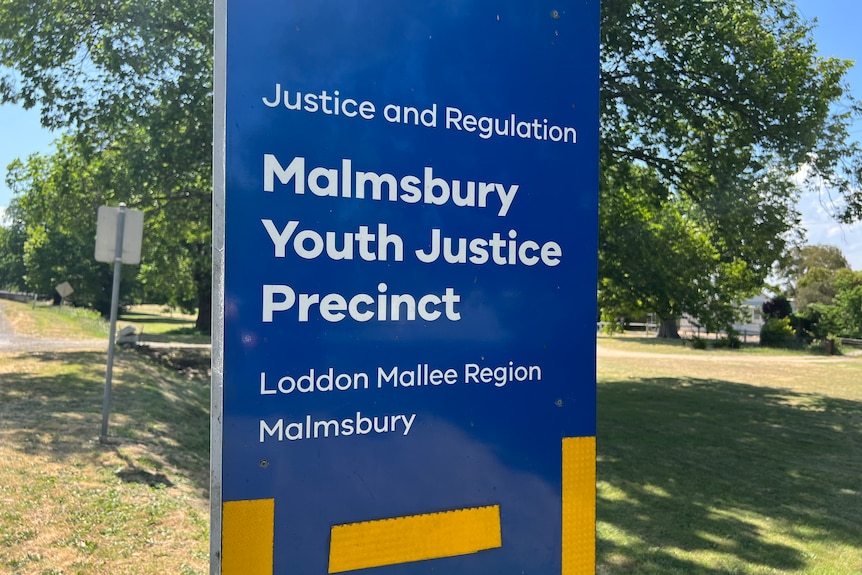 A blue sign that says Malmsbury Youth Justice Precinct.