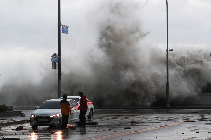 Waves crash over the breakwater in Busan