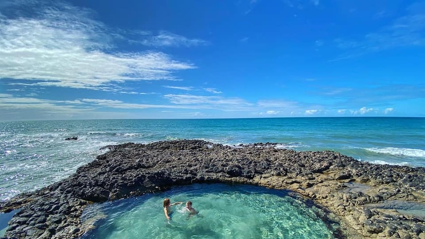 Two boys swim in crystal clear lagoon off Elliot Heads