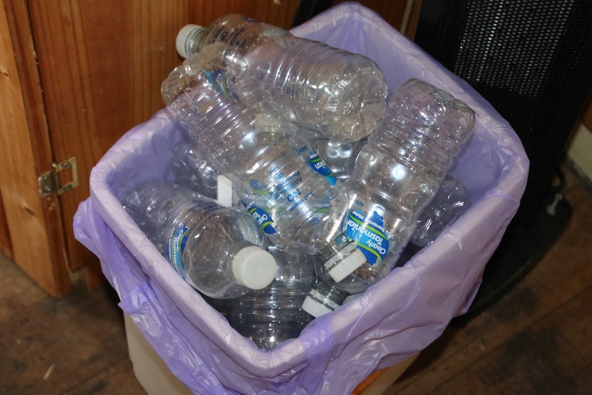 A rubbish bin full of empty water bottles.