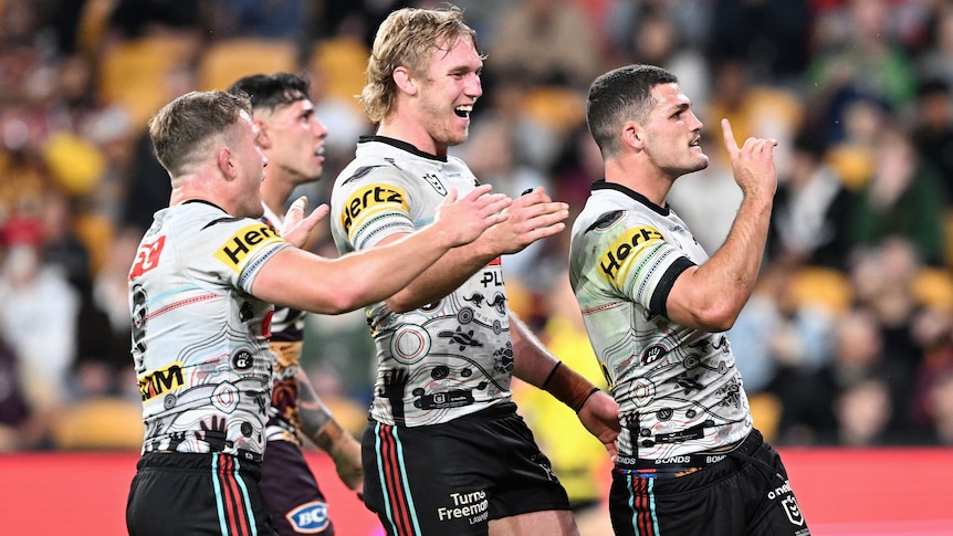 Three Penrith NRL players celebrate a try against the Broncos.