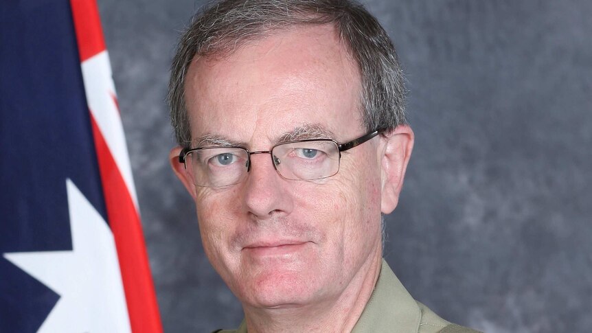 Major General Brereton's official portrait, in uniform and posed in front of an Australian flag. He's wearing glasses.