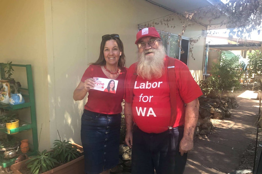 A middle aged woman and an older man with a beard pose in Labor t-shirts.