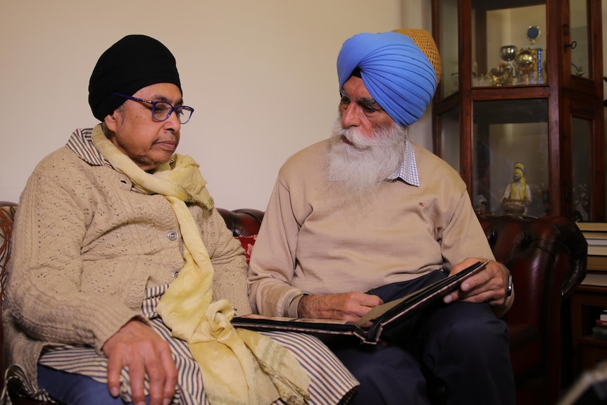 A mid shot of Jatinderpal Singh and Jagkeerat Kaur, sitting on couch looking at photo album 