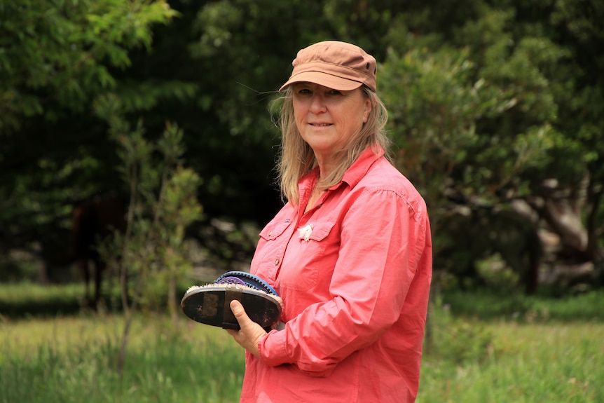 Sally Campbell stands outside in a paddock wearing a pink shirt and light orange cap.