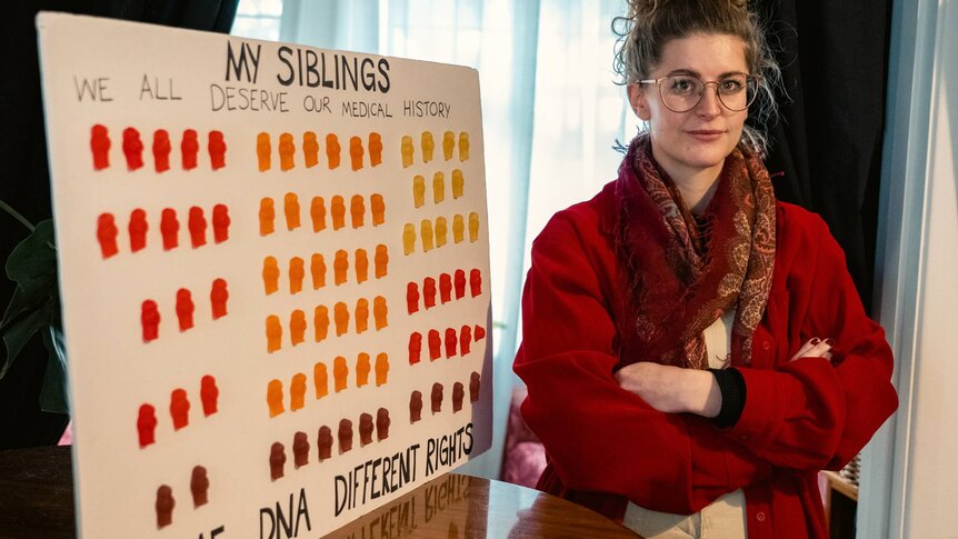 A woman stands next to a sign saying "my siblings"