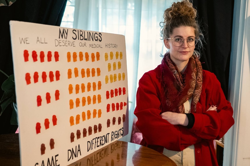 A woman stands next to a sign saying "my siblings"