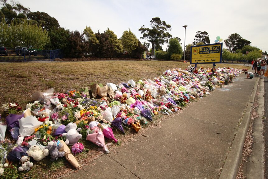 Hundreds of bunches of flowers under a sign reading Hillcrest Primary School