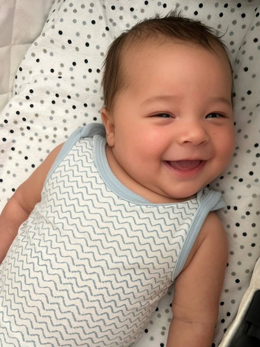 A baby smiles at the camera